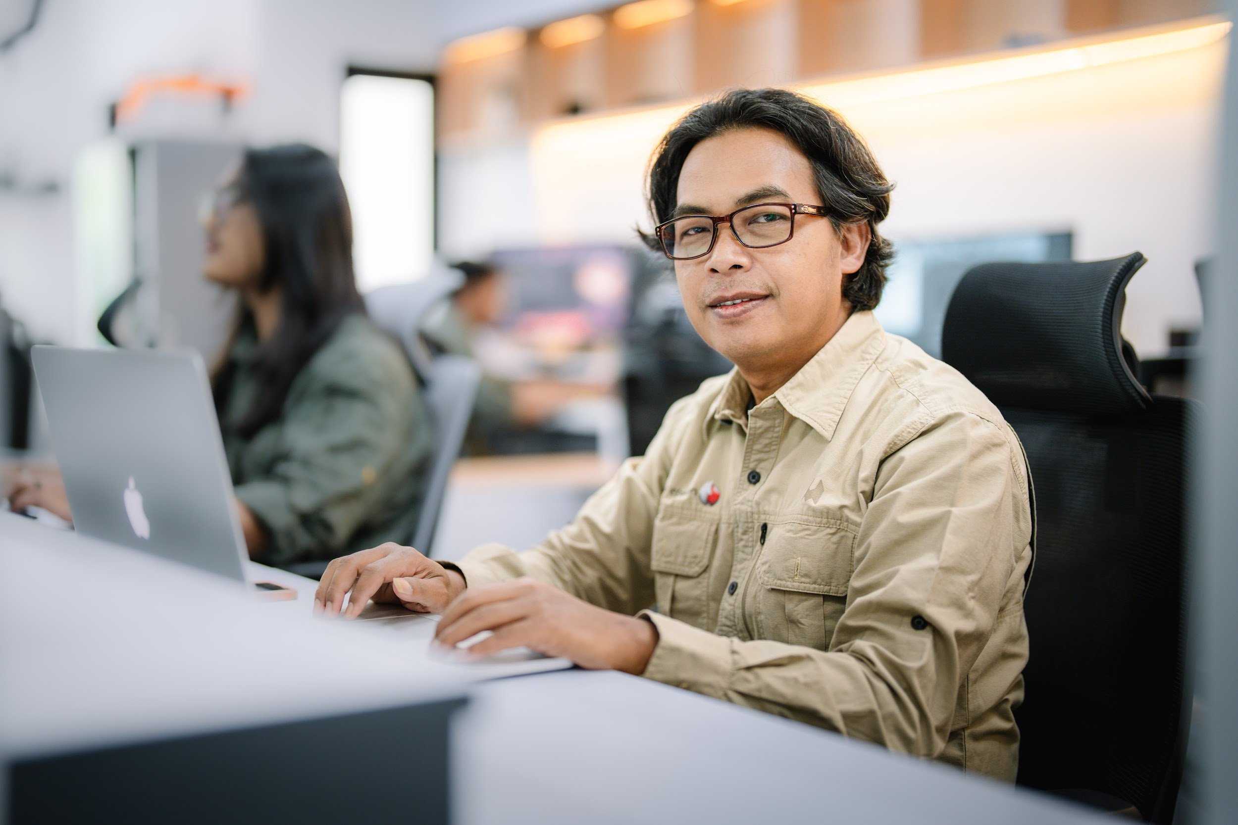 Seorang analis tersenyum di depan laptop di ruang kantor